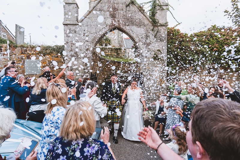 Bride and groom walking through confetti after their wedding ceremony