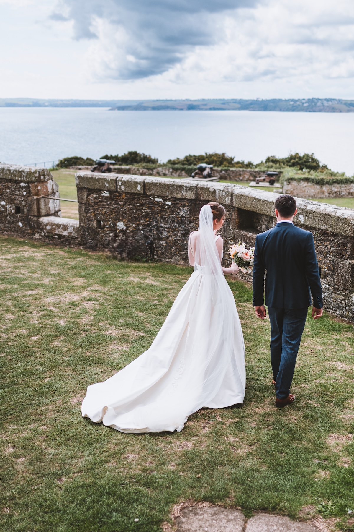 A bride and groom sharing a quiet moment by St Dennis Castle in Falmouth Cornwall captured by a documentary wedding photographer.