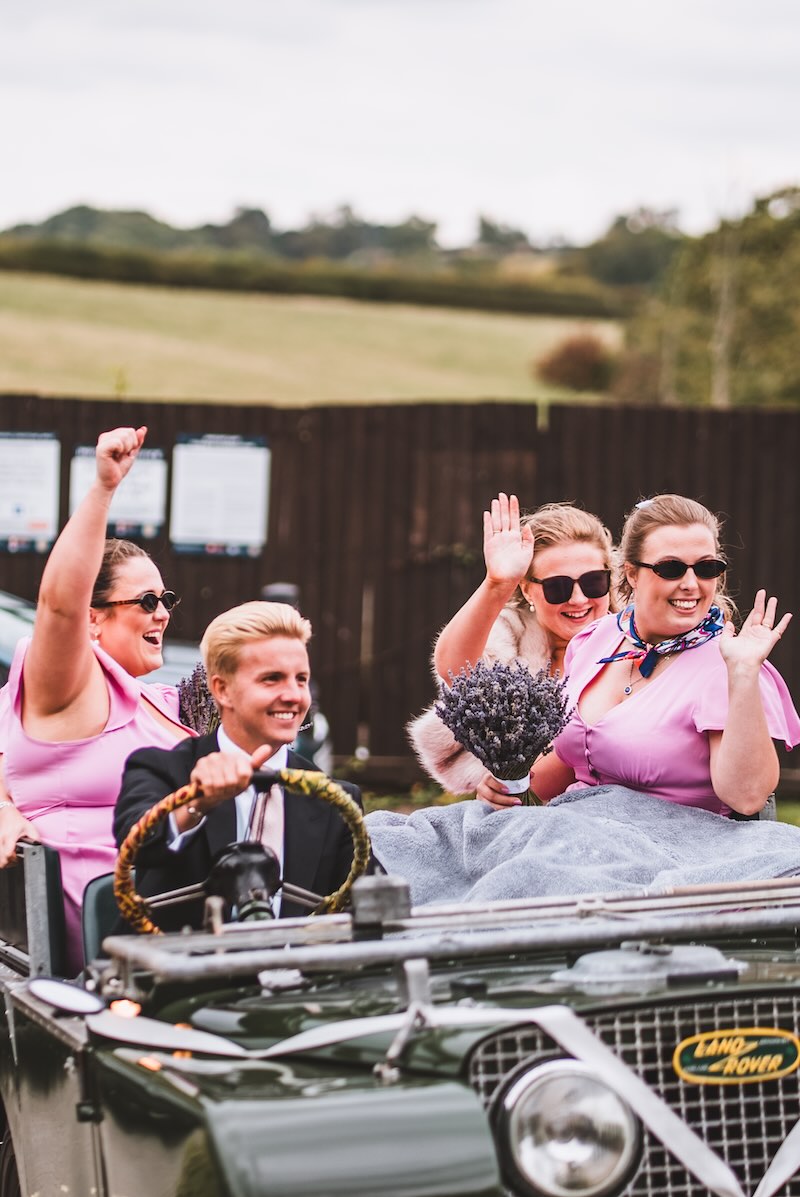 An old Land Rover transporting bridesmaids captured by UK wedding videographers