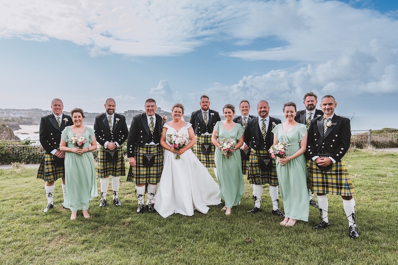 Wedding party group photo with the Newquay coastline in the background