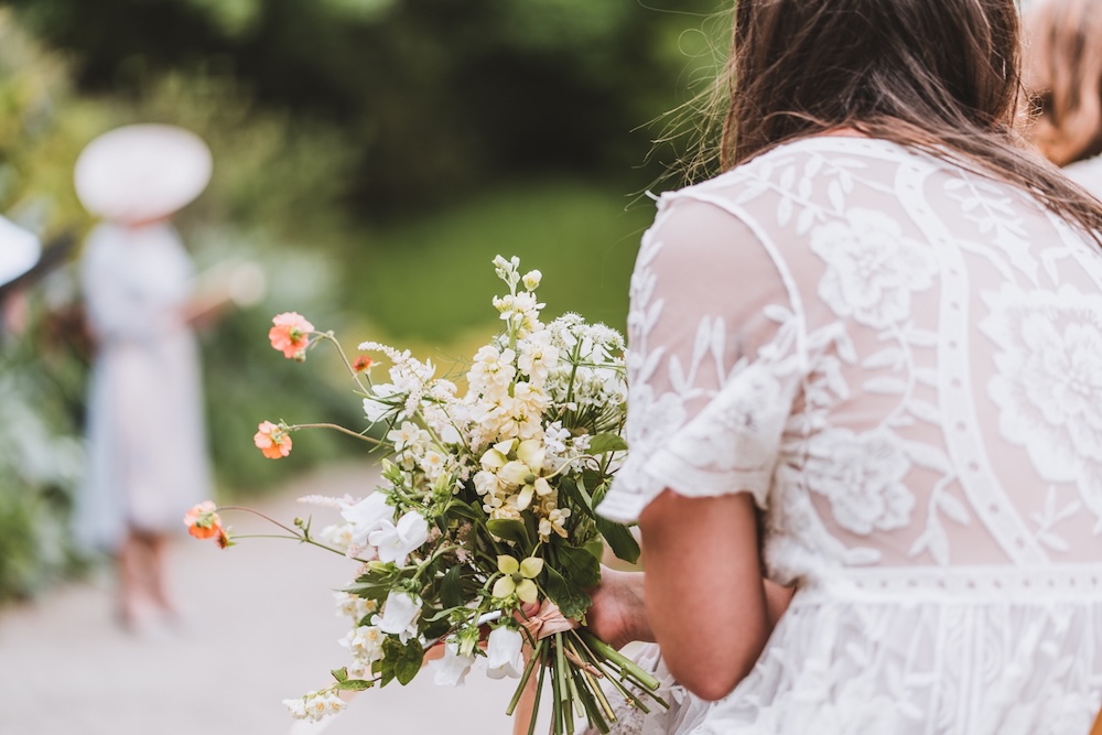 A close focus on bridesmaid flowers as she looks over a festival wedding for a pricing record.