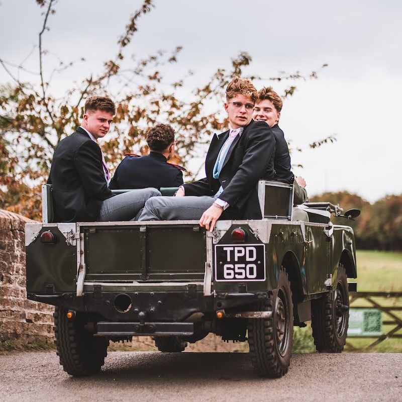 A vintage Land Rover transporting the groom and groomsmen across a Berkshire estate, captured in a documentary style.