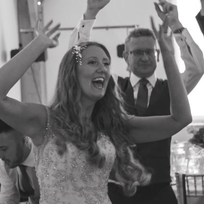 A cinematic still from a Devon wedding motion record at Glebe House Cottages, capturing the warm sunshine and unscripted energy.